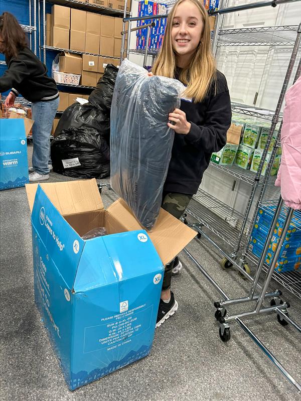 girl packing blankets in a box